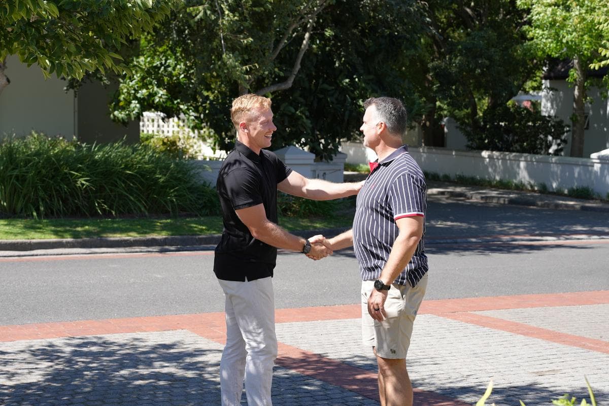 Rainer Jonker shaking hands with a property client on a tree-lined street in Paarl